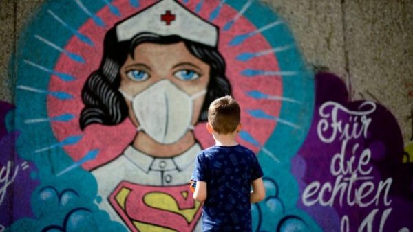 Un garçon se tient devant un graffiti peint par l’artiste Kai 'Uzey' Wohlgemuth à Hamm, en Allemagne de l’Ouest, le 8 avril 2020. ©️ AFP via Getty Images