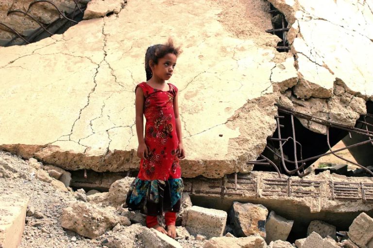 Une fillette yéménite, déplacée avec sa famille, se tient au milieu des ruines d’un immeuble détruit par des frappes aériennes de la coalition menée par l’Arabie saoudite, dans la province de Hajjah au nord-ouest du Yémen, le 3 août 2019 © AFP