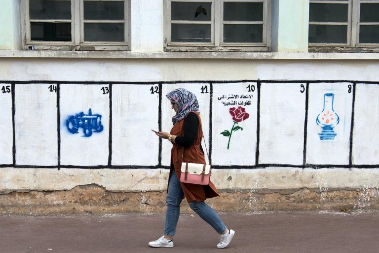 Une Marocaine passe devant des emplacements où sont peints les symboles des partis politiques du Royaume, le 4 septembre 2015 © AFP/Archives