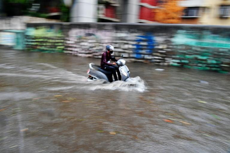 Un homme à scooter se fraie un passage dans une rue inondée à l'approche du cyclone Tauktae, à Bombay, en Inde, le 17 mai 2021 © AFP